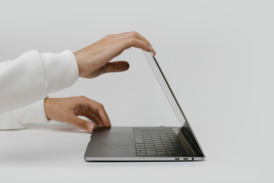 Minimalist photo showing hands opening a sleek laptop, perfect for technology and lifestyle themes.